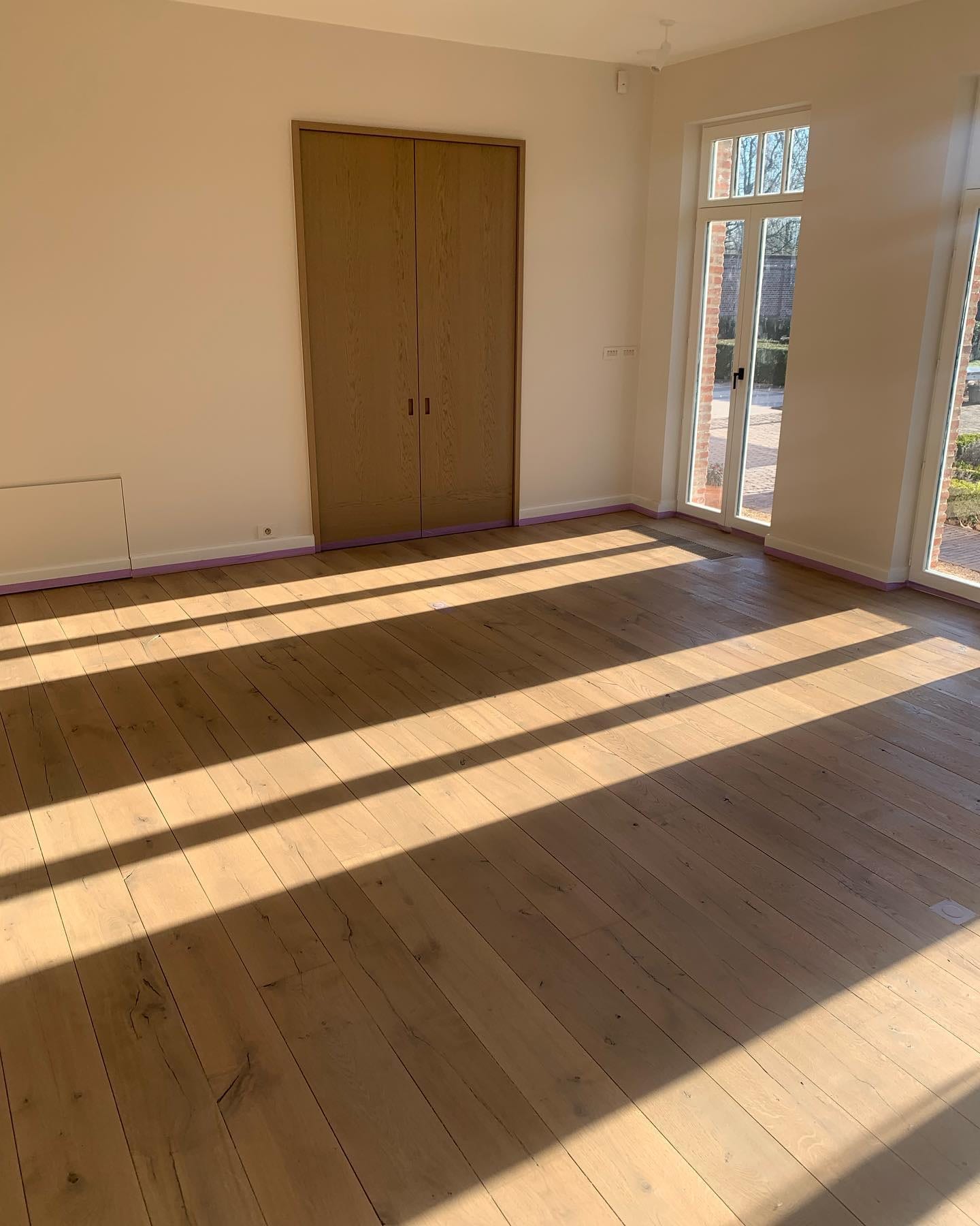 Warme eiken plankenvloer in een lege kamer, het zonlicht tekent de nerf van het hout