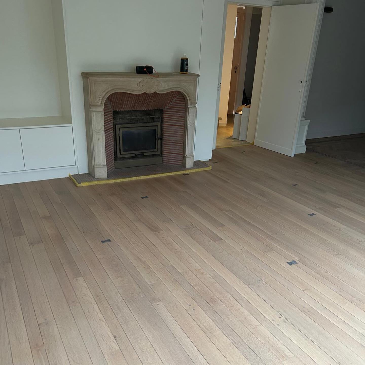 Woonkamer met marmeren schouw waarvan de eiken plankenvloer net geschuurd en nog onbehandeld is