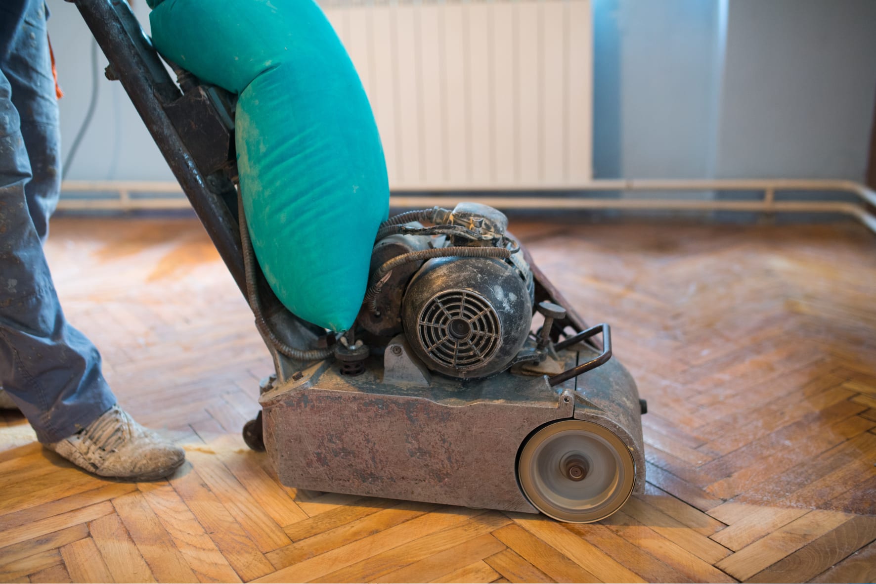 Parketschuurmachine die een oude eiken visgraatvloer laag per laag terugbrengt naar kaal hout