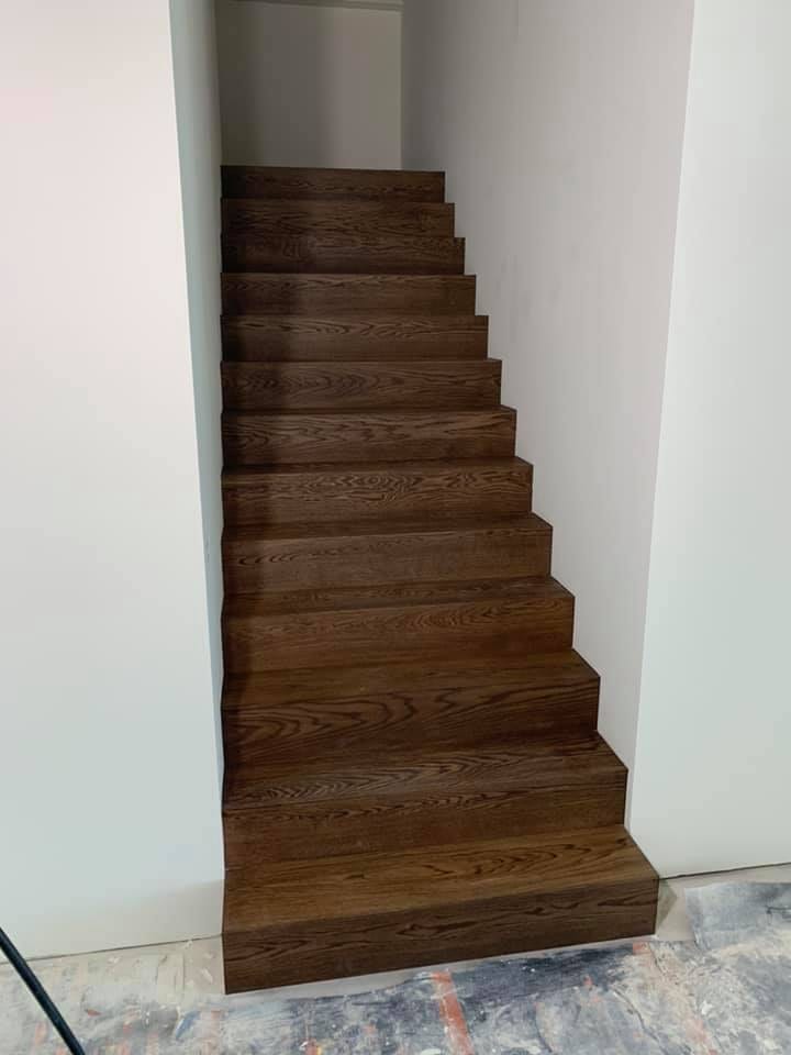 Volledig met donker hout beklede trap, treden en stootborden strak op maat gezaagd