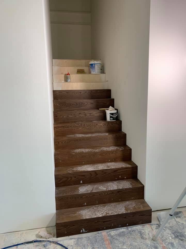 Detail van een met hout beklede trap tijdens de werken, met de eerste treden afgewerkt